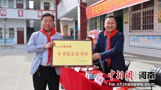 图为金沙2004路线js5党委副书记孙海(右1)将“小书虫”公益书屋的牌匾交到关爷庙小学校长杨少许手中。